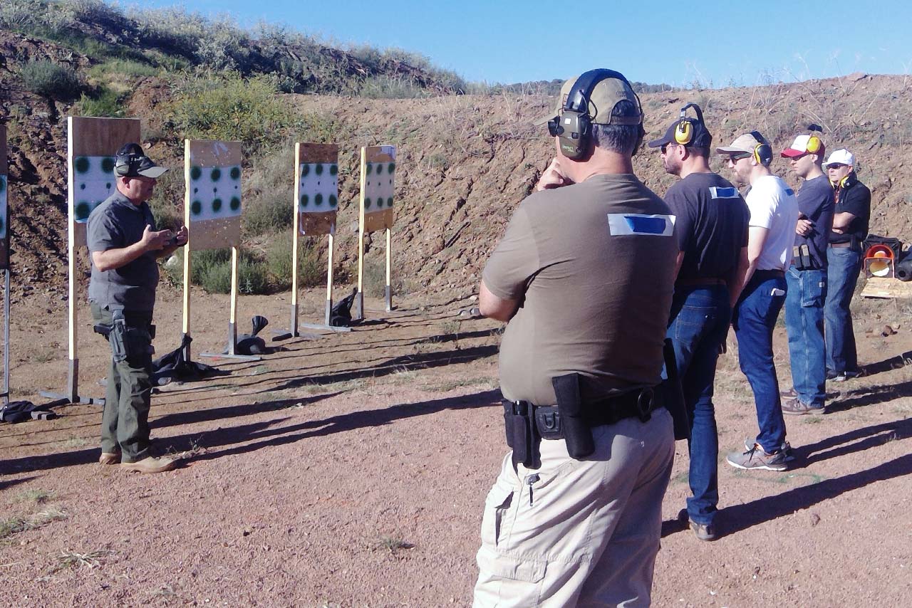 firearms instructor speaking with group of trainees on shooting range
